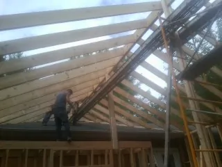 Rafters going up over a new addition with a worker on the wall in Seguin