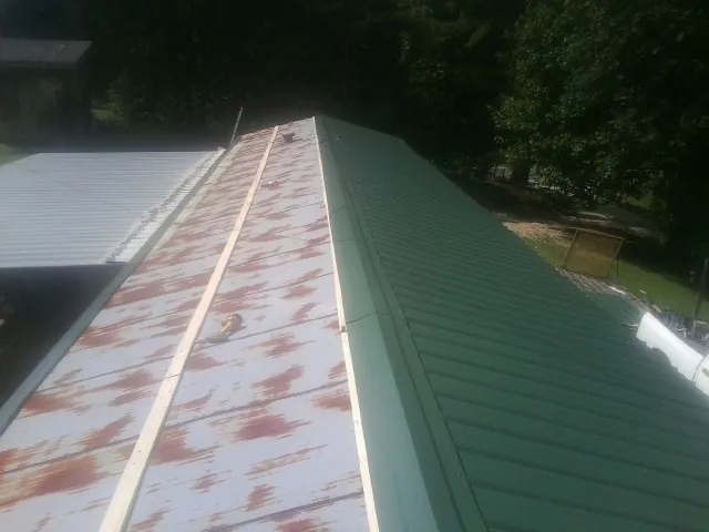 Old rusted panels beside newly installed green metal roofing — Wind Damage Roof Repair by Roofing Brothers in Seguin
