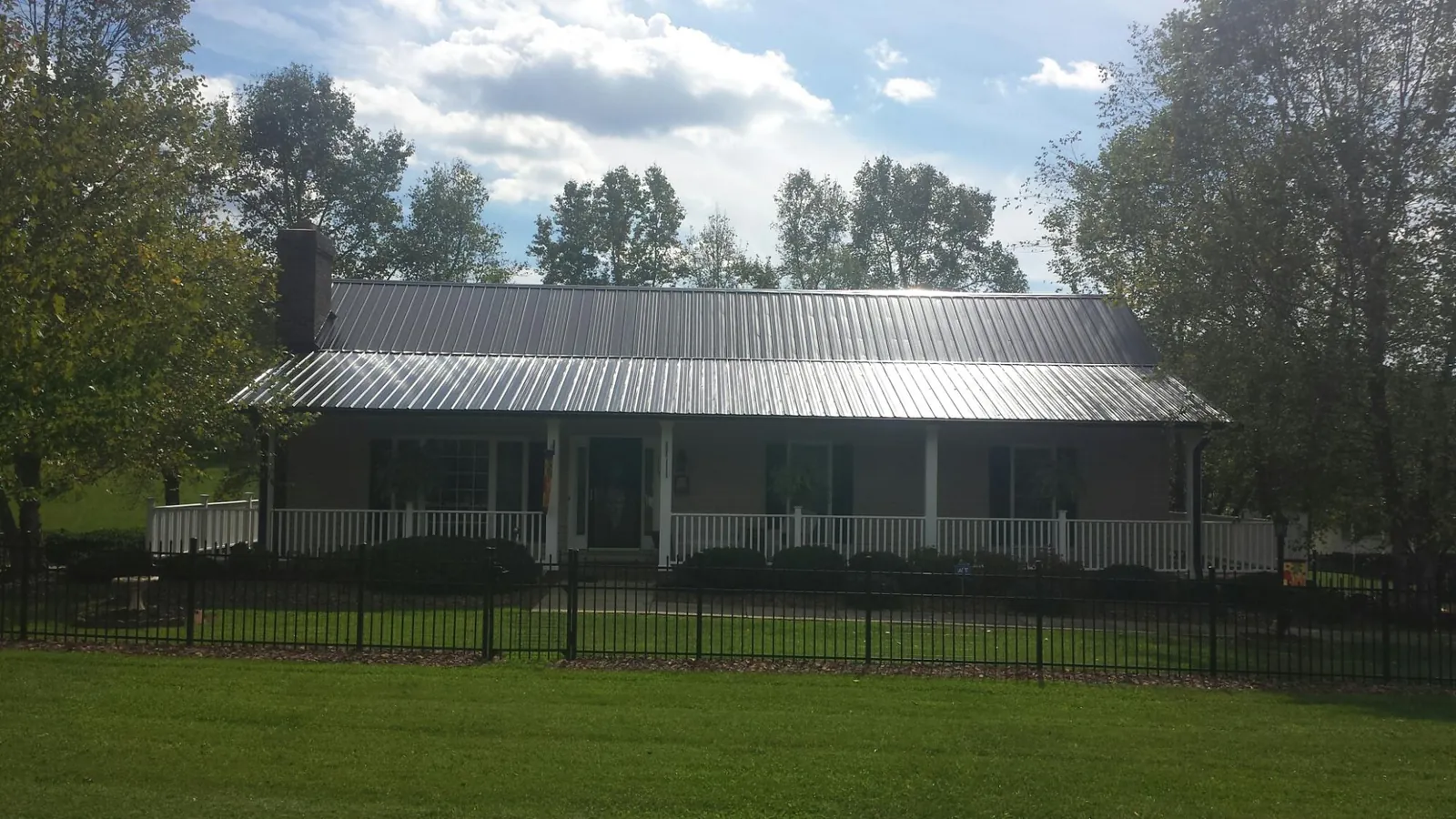 Gray metal roof on a brick ranch with a full width front porch — Gutter Guard Installation work by our crew in Seguin