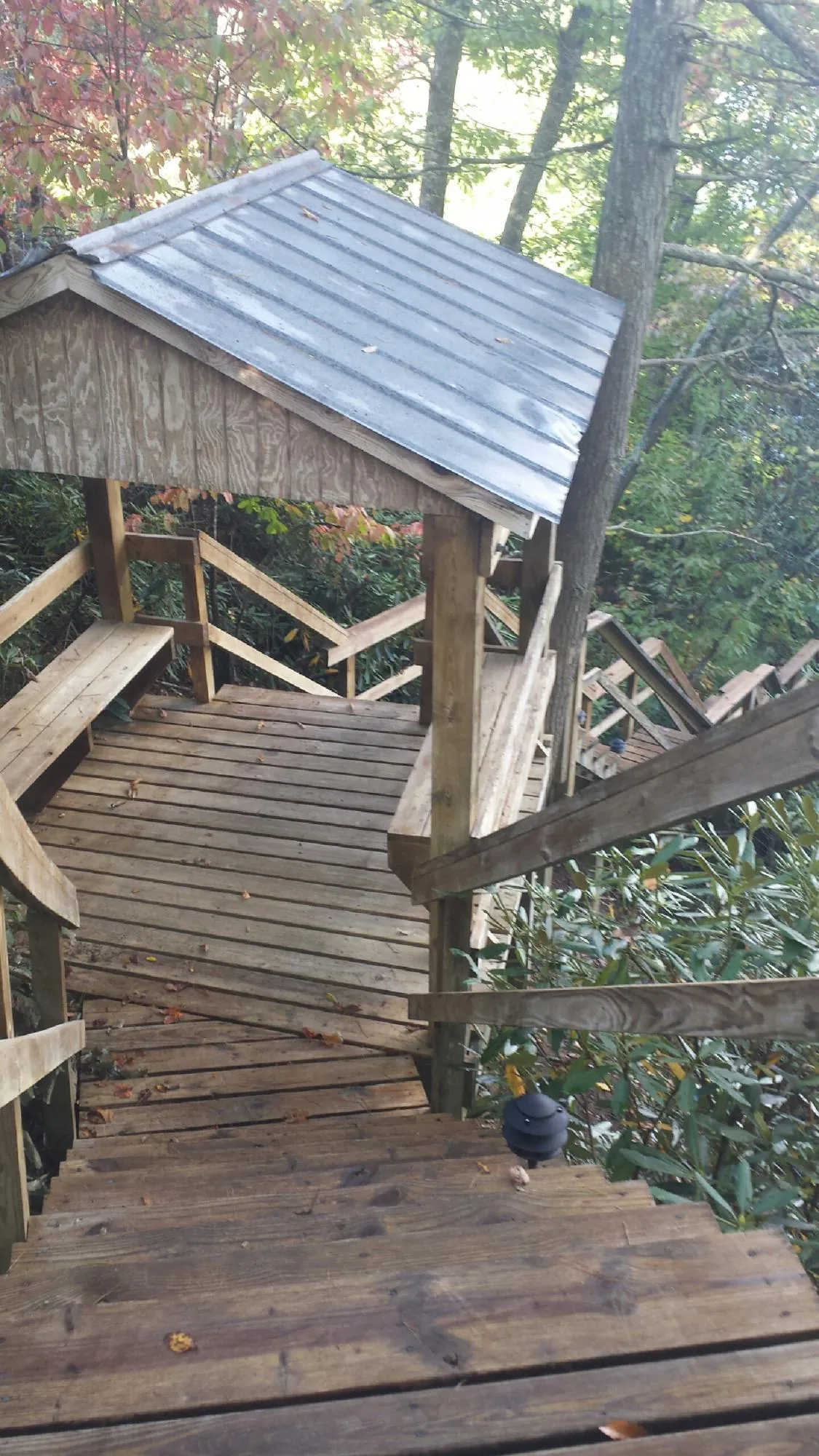 Metal roofed shelter over wooden steps on a wooded walkway — Skylight Repair & Installation work by our crew in Seguin