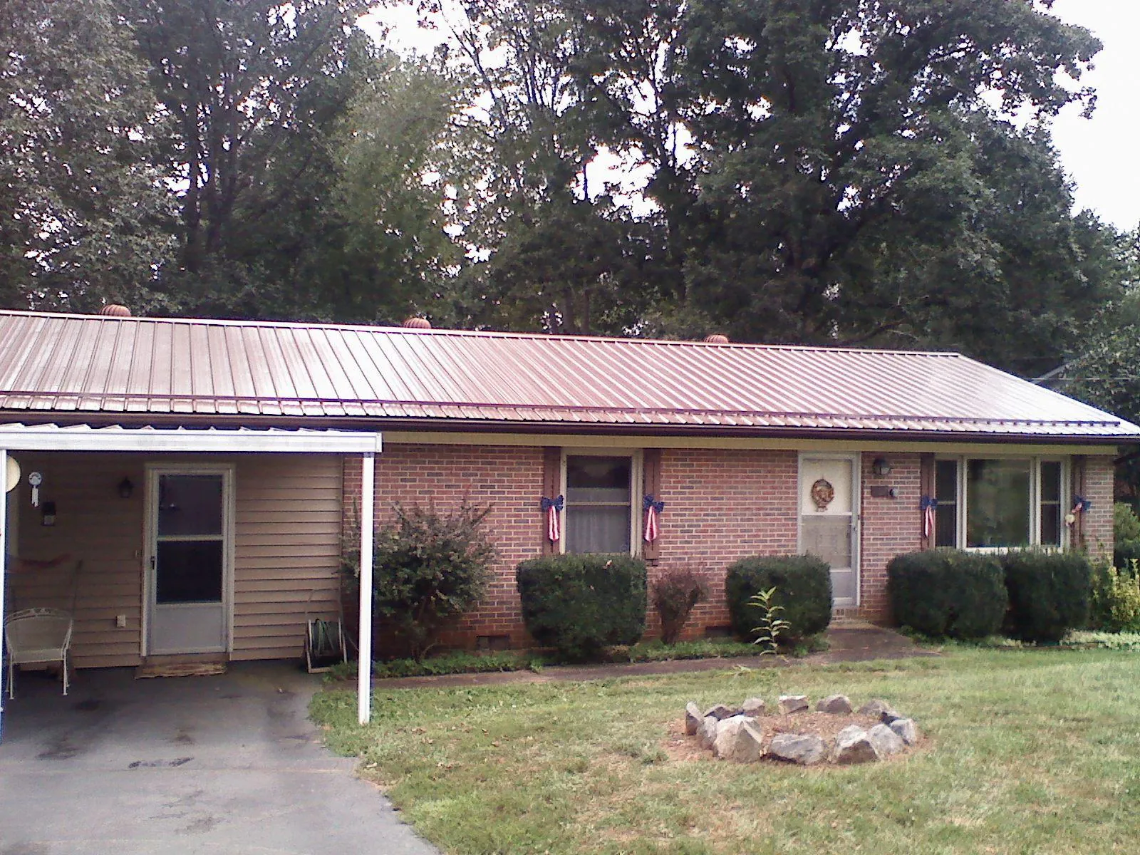 Bronze metal roof and carport on a brick ranch home — Roof Repair work by our crew in Seguin