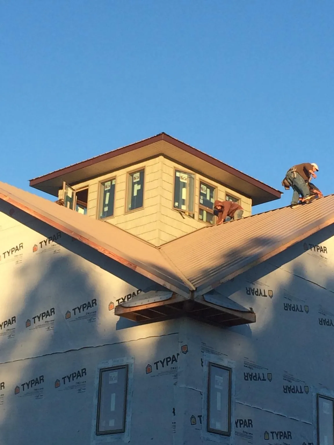 Roofers working around a rooftop cupola on a new metal roof at sunset — Roof Waterproofing in Seguin by Roofing Brothers